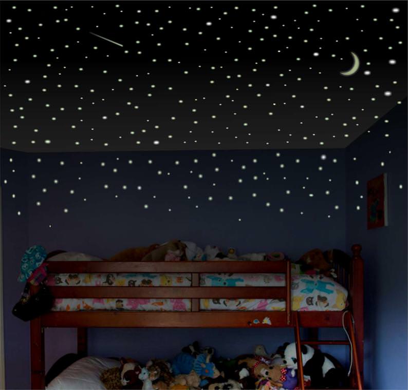 اتاق خواب کودک با تخت دو طبقه که سقف و بخشی از دیوار آن با استیکرهای شب تاب ماه و ستاره تزیین شده است